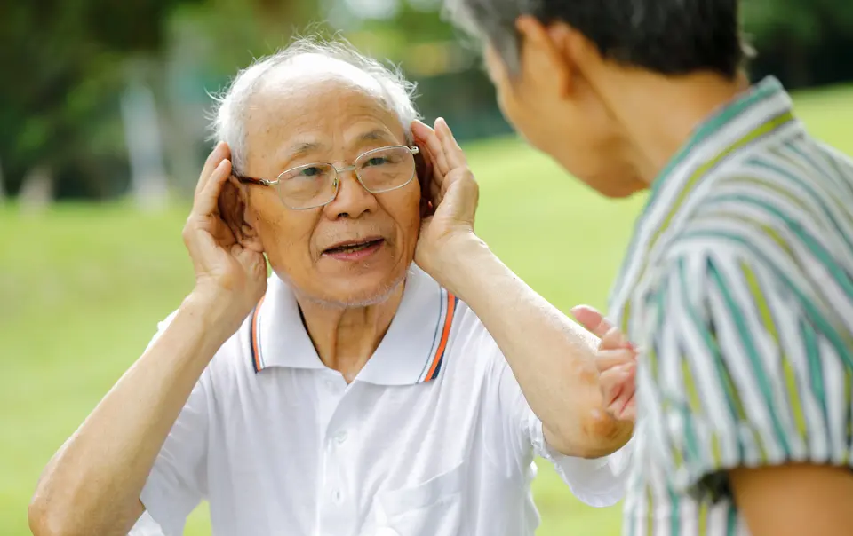 以双手掩耳、想听得更清楚的老年男性